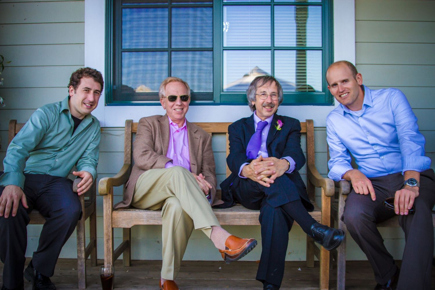 Four people relaxing on wooden rocking chairs on a rustic front porch.