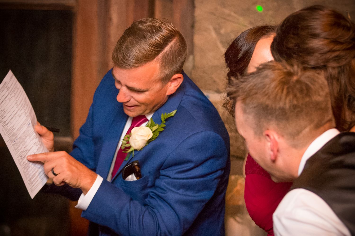 A group gathers closely to read documents at a formal occasion.