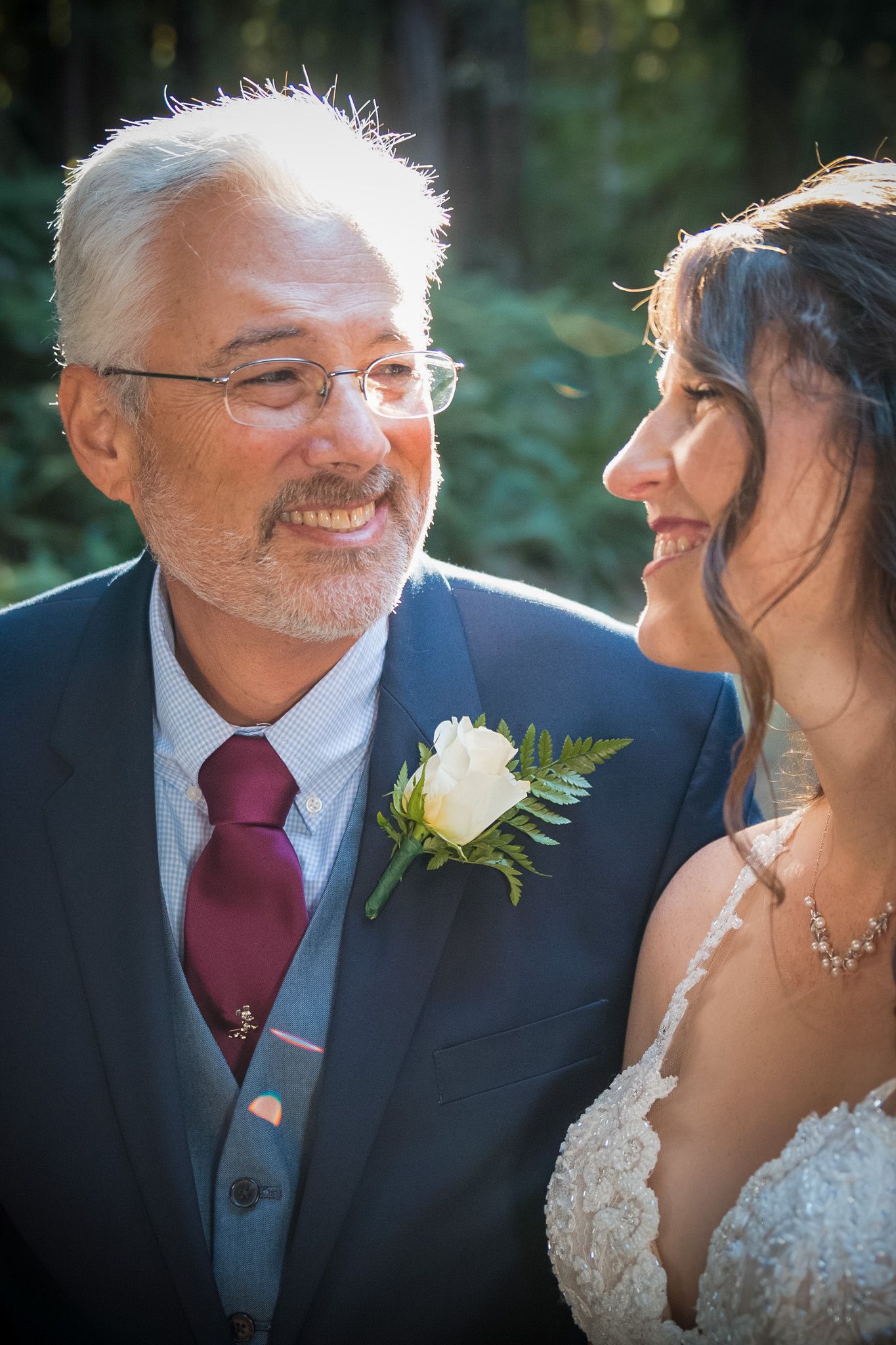 Heartwarming moment between bride and father figure during outdoor wedding portraits.