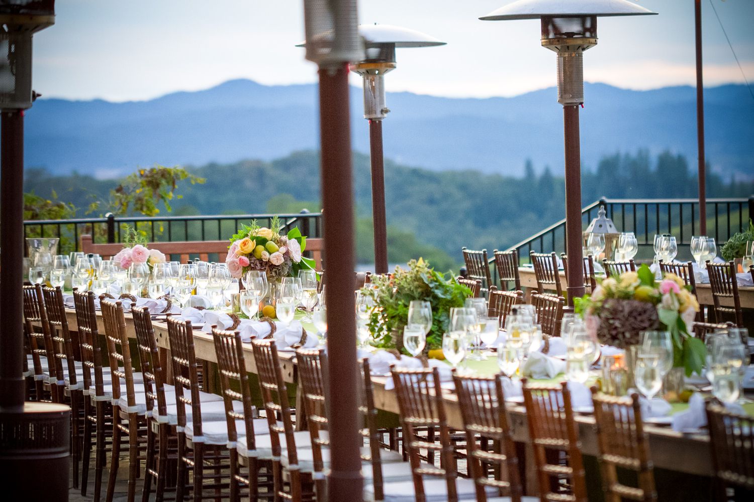 Elegant outdoor winery reception table setup with mountain views and string lights.
