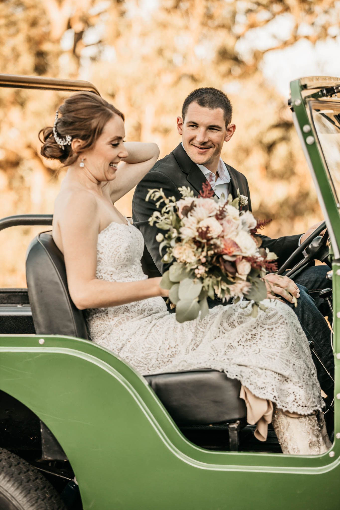A couple sharing a joyful moment together in a vintage green vehicle on their wedding day.