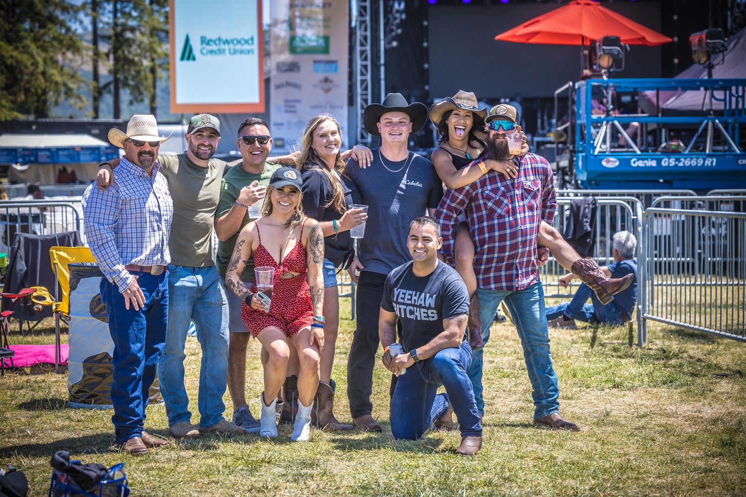 Group photo at outdoor music festival with stage backdrop.