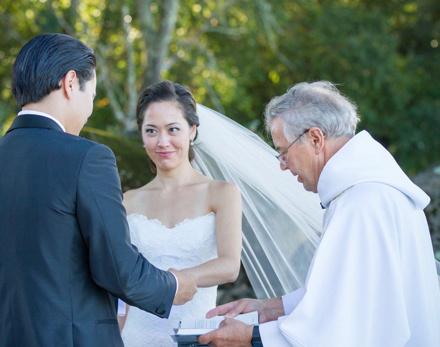 Wedding ceremony moment with couple and officiant exchanging vows outdoors.