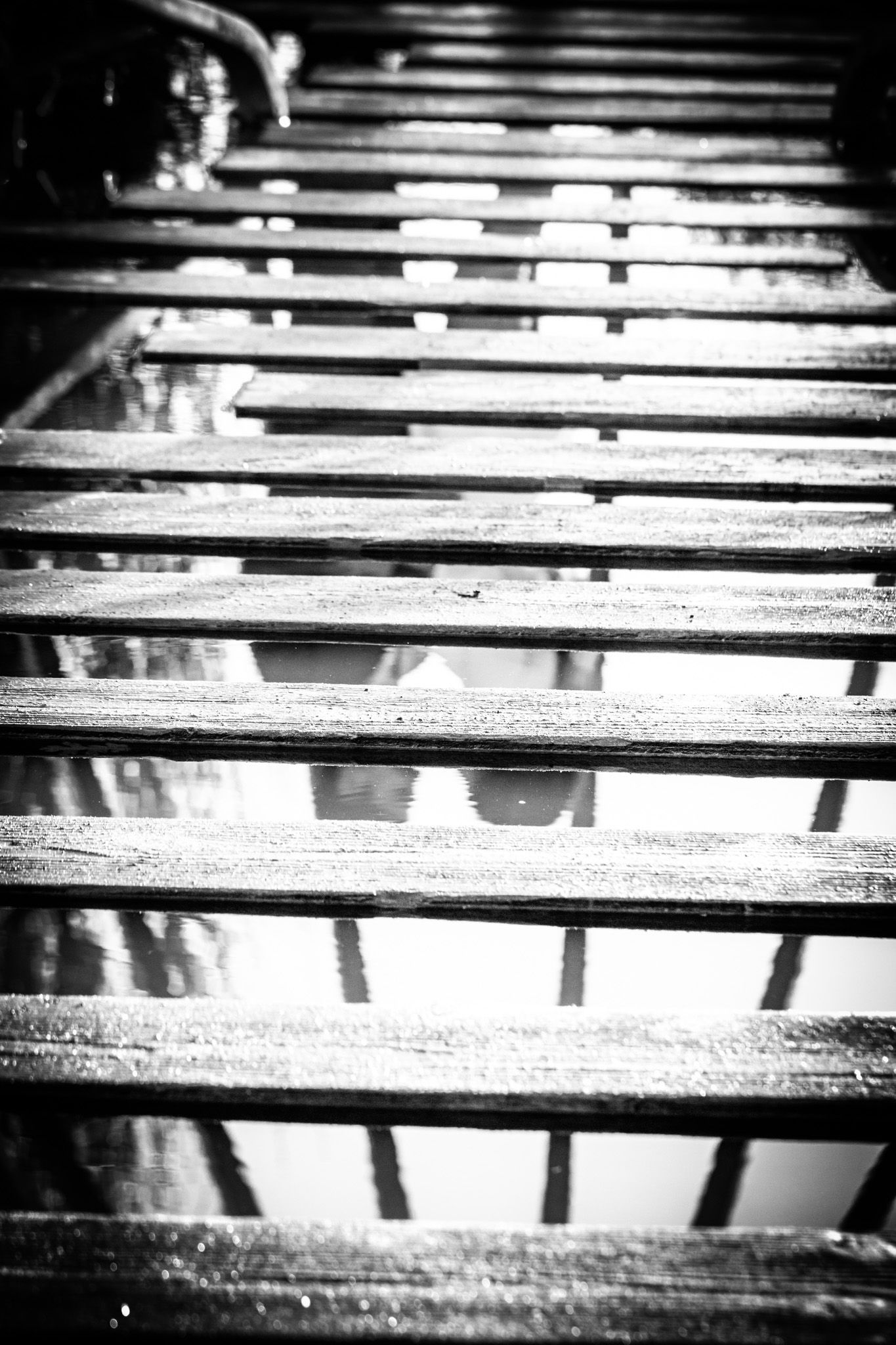 Black and white photograph of wooden slats creating dramatic shadows and lines in an abstract pattern.