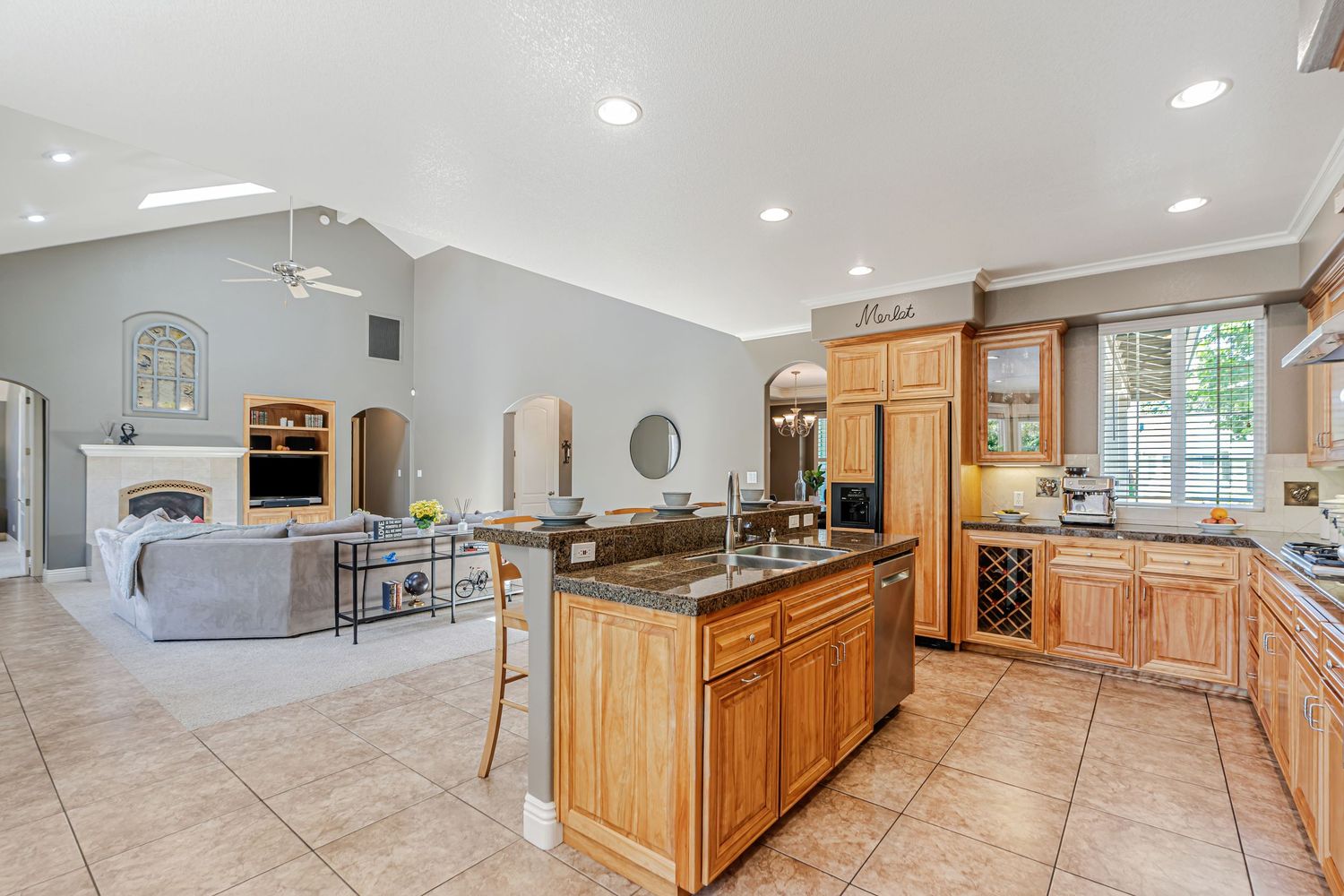 Spacious open concept kitchen with honey oak cabinets flowing into living room with stone fireplace.