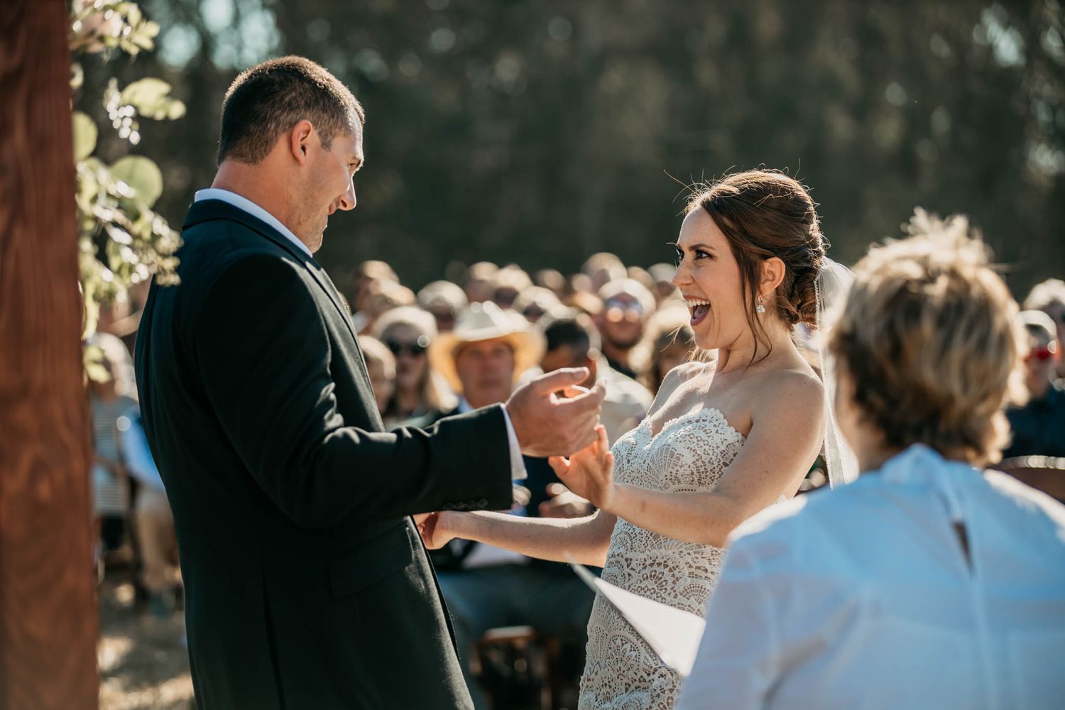 Outdoor wedding ceremony with decorated arch and natural surroundings.