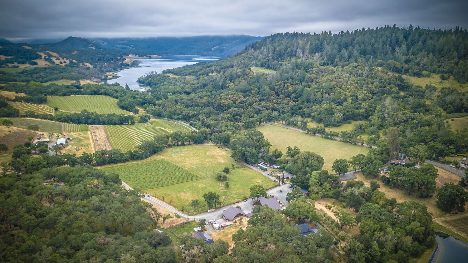 Aerial view of rural property surrounded by forested hills and winding river.