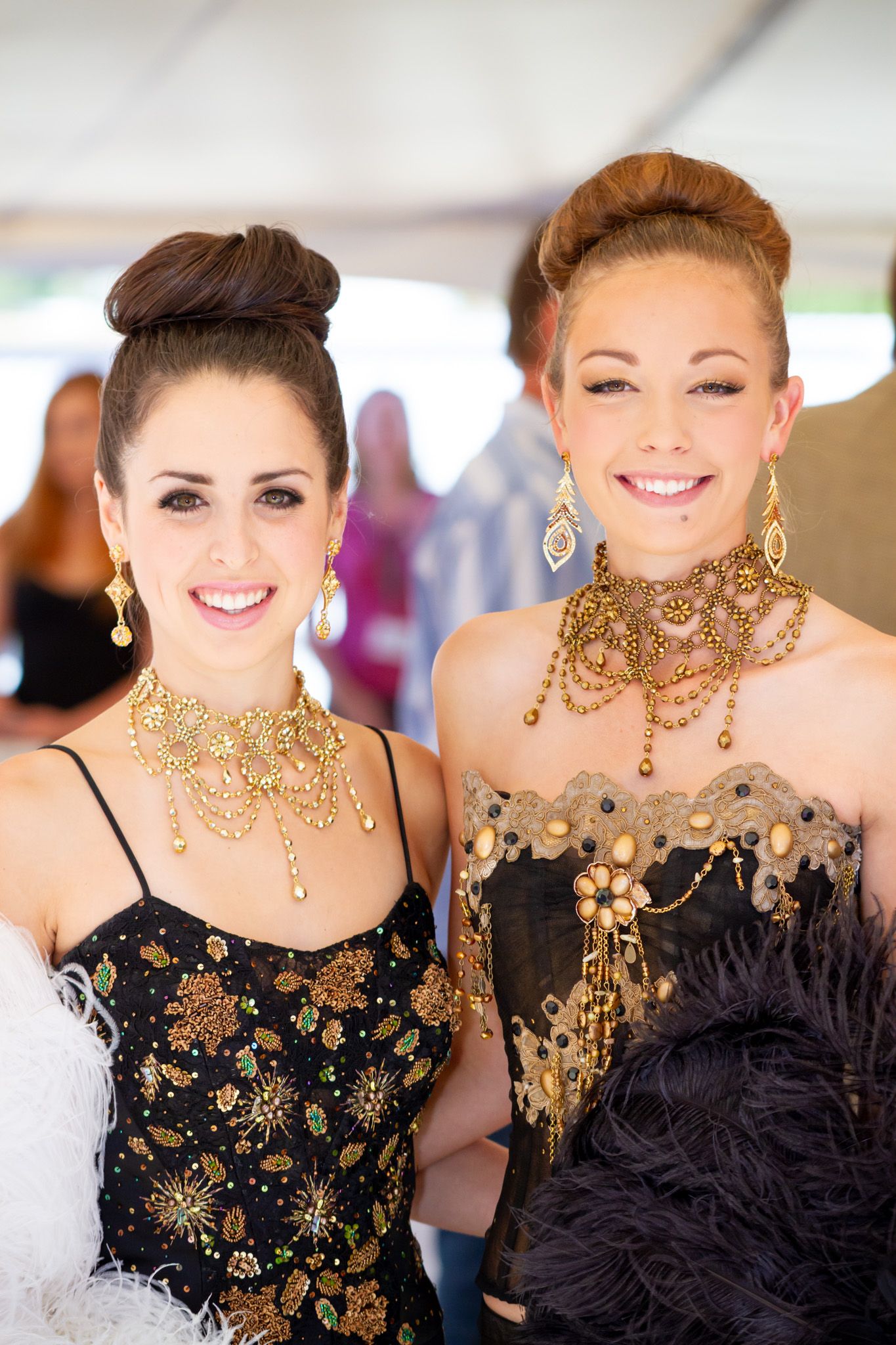 Two women in formal attire wearing elaborate gold necklaces and evening gowns.