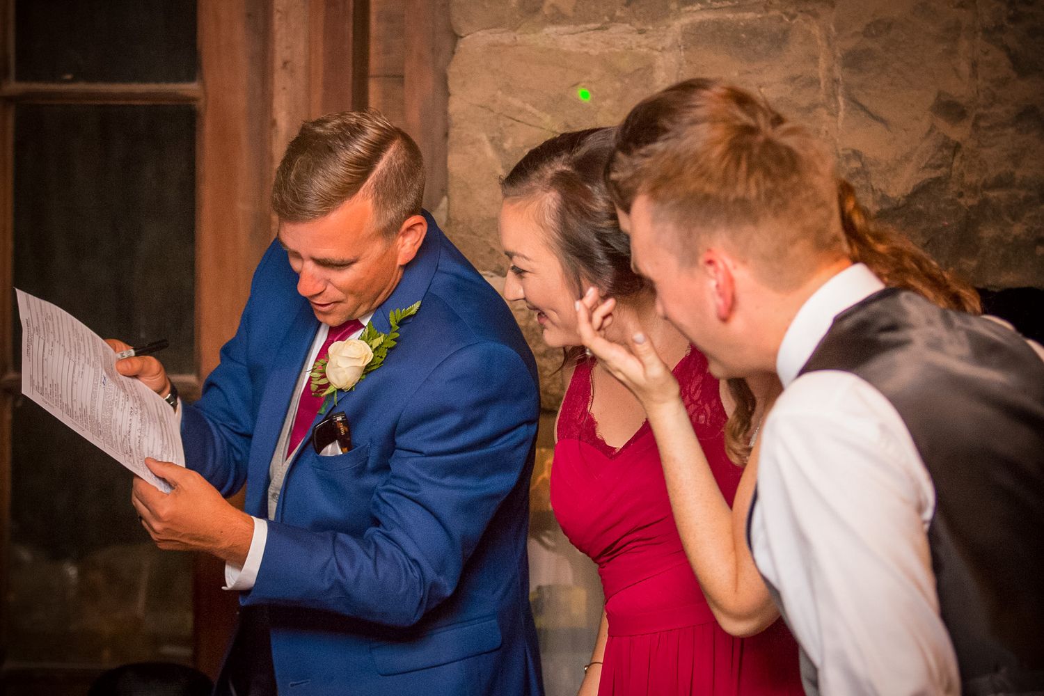 A group reads from papers while showing emotional reactions at an indoor venue.
