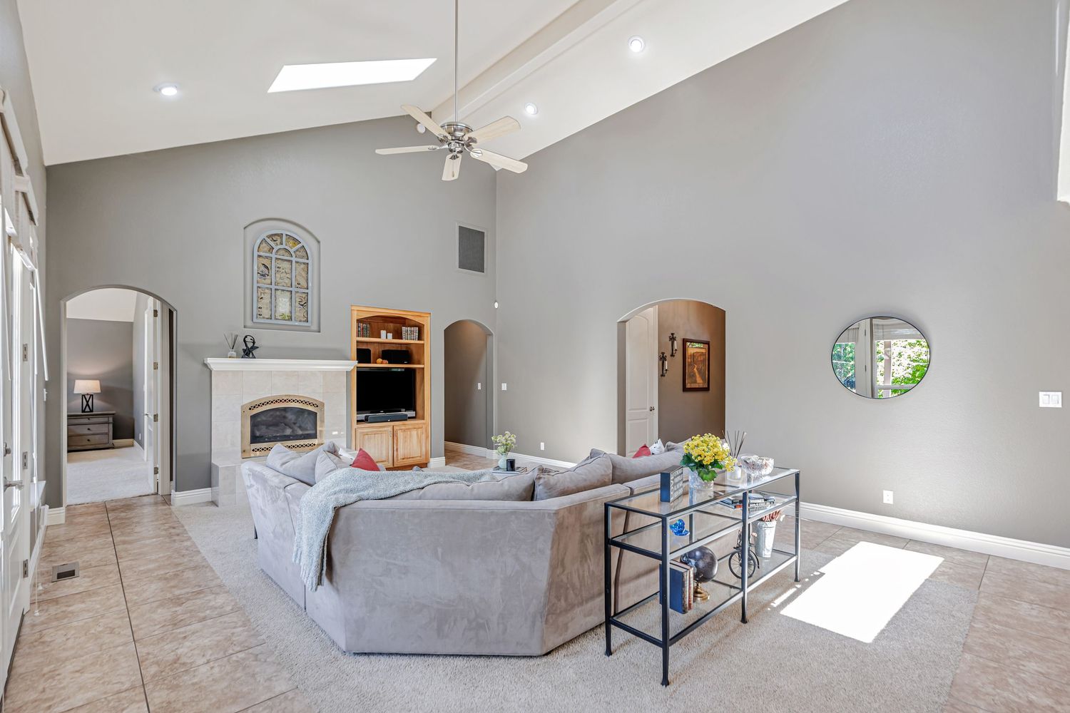 Bright living room with cathedral ceiling, built-in entertainment center, and comfortable seating arrangement.