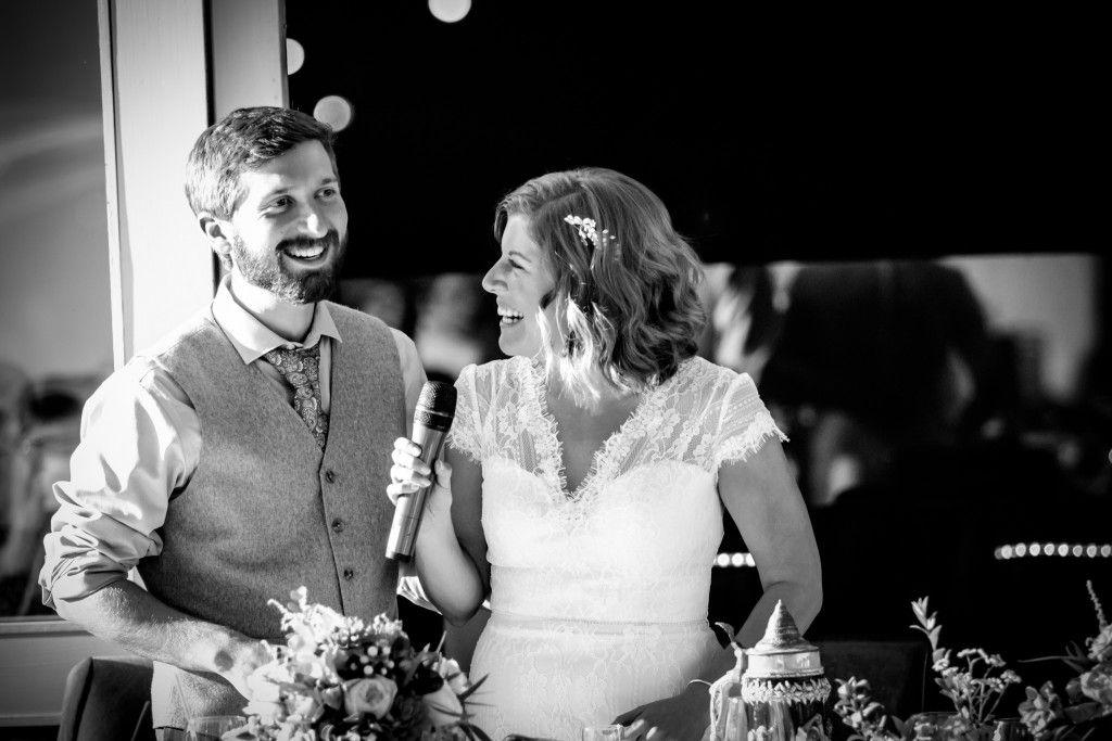 Black and white candid photo of joyful moments during wedding reception speeches.