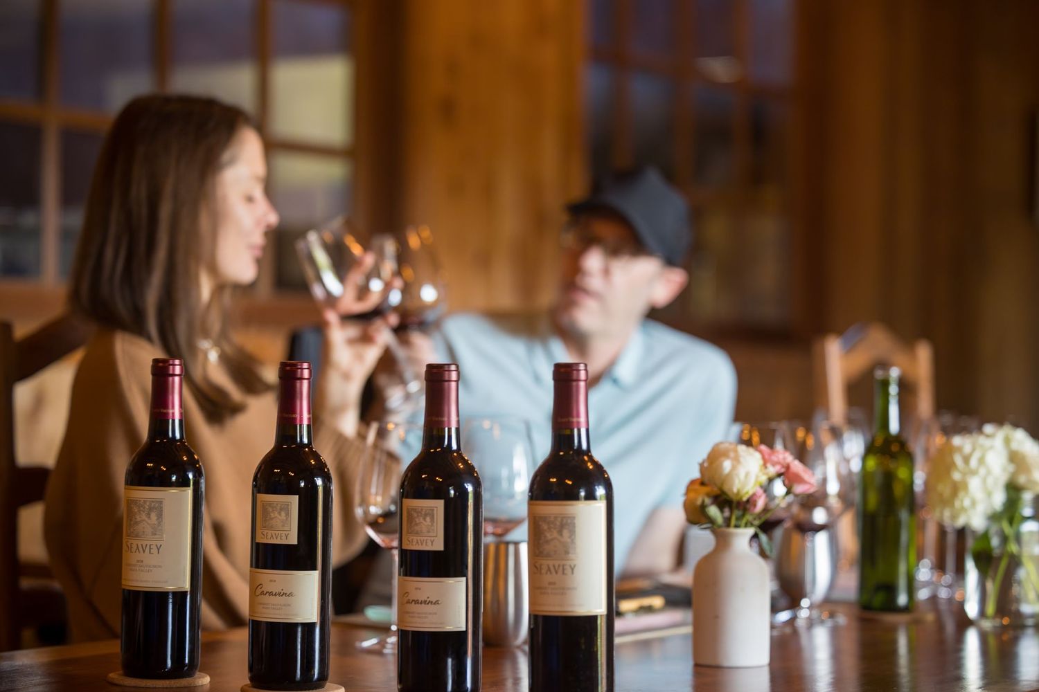 Wine tasting setup with multiple bottles displayed on rustic wooden table in a cozy tasting room.