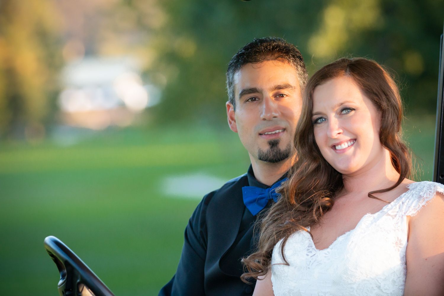 Wedding portrait of a couple in formal attire on a golf course at sunset.