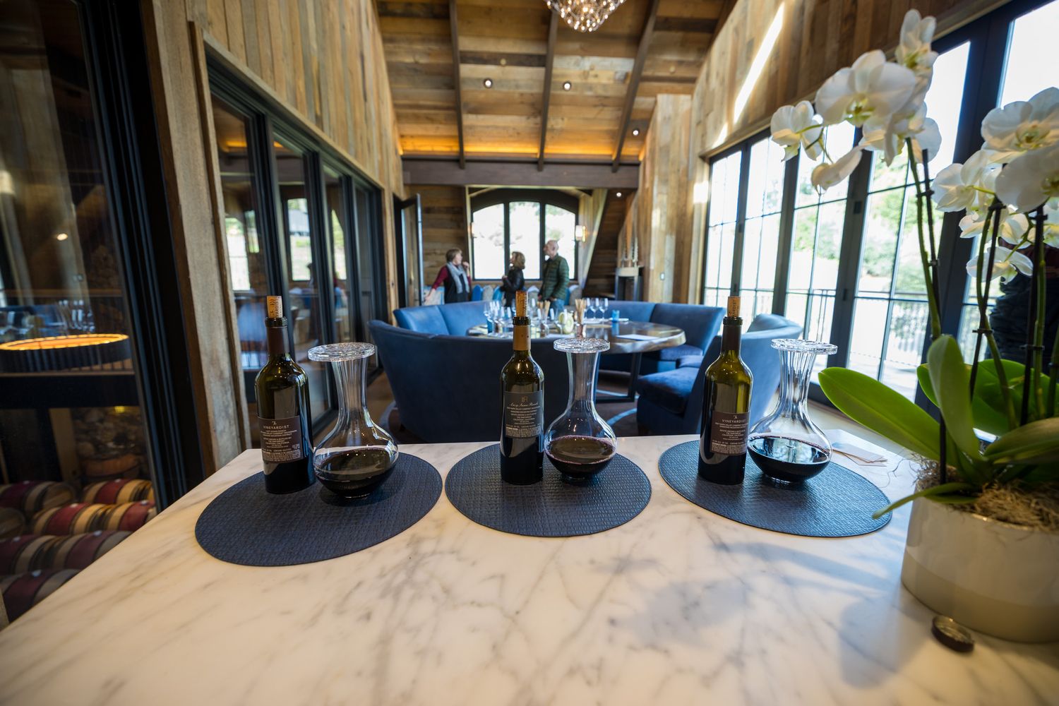 Wine bottles displayed on a white marble counter with decorative orchids in an upscale dining setting.