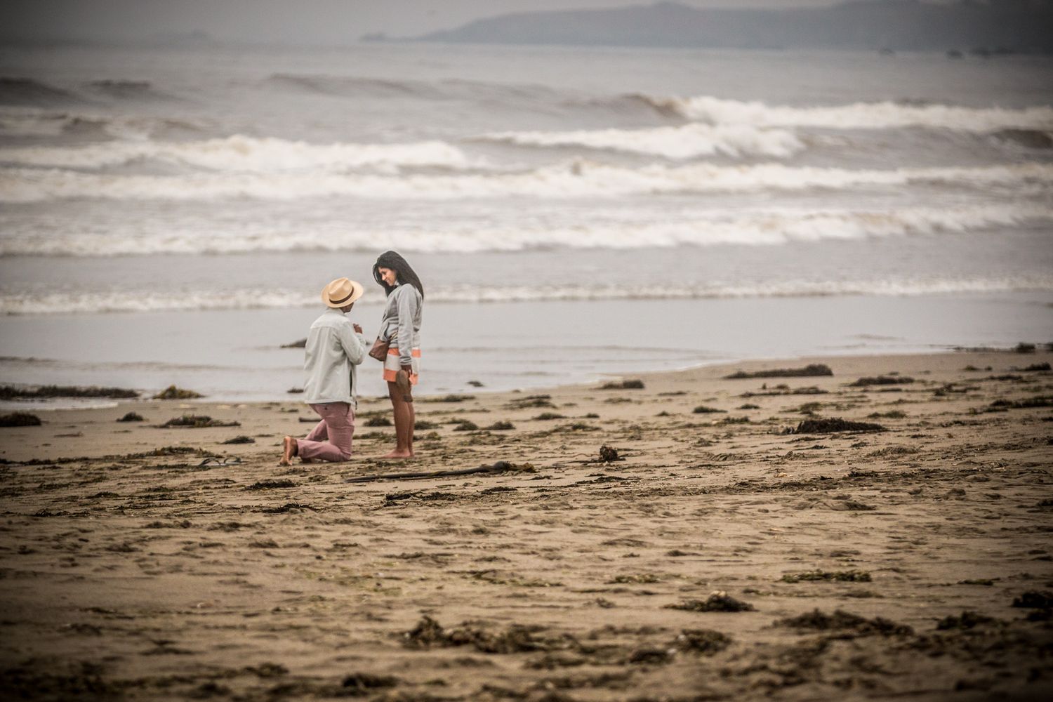 Atmospheric scene of two people exploring a foggy beach together.