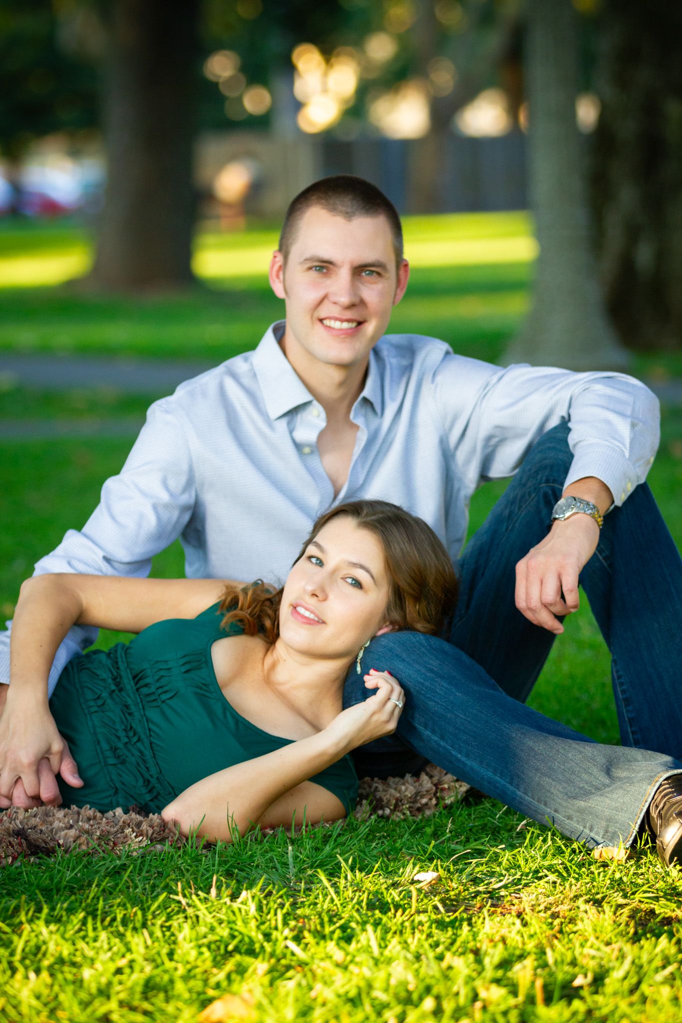 Couple relaxing together on lush green grass in a park on a sunny day.