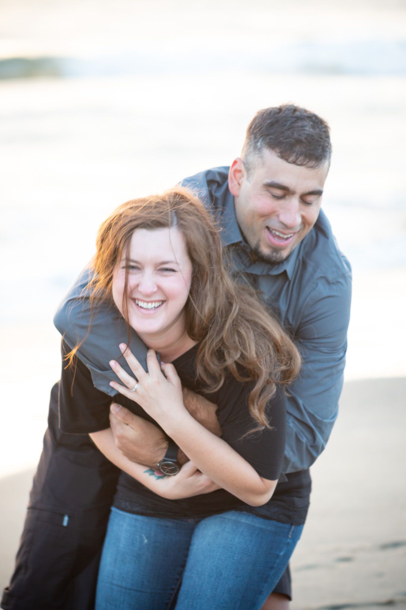Joyful couple embracing and laughing together on beach.