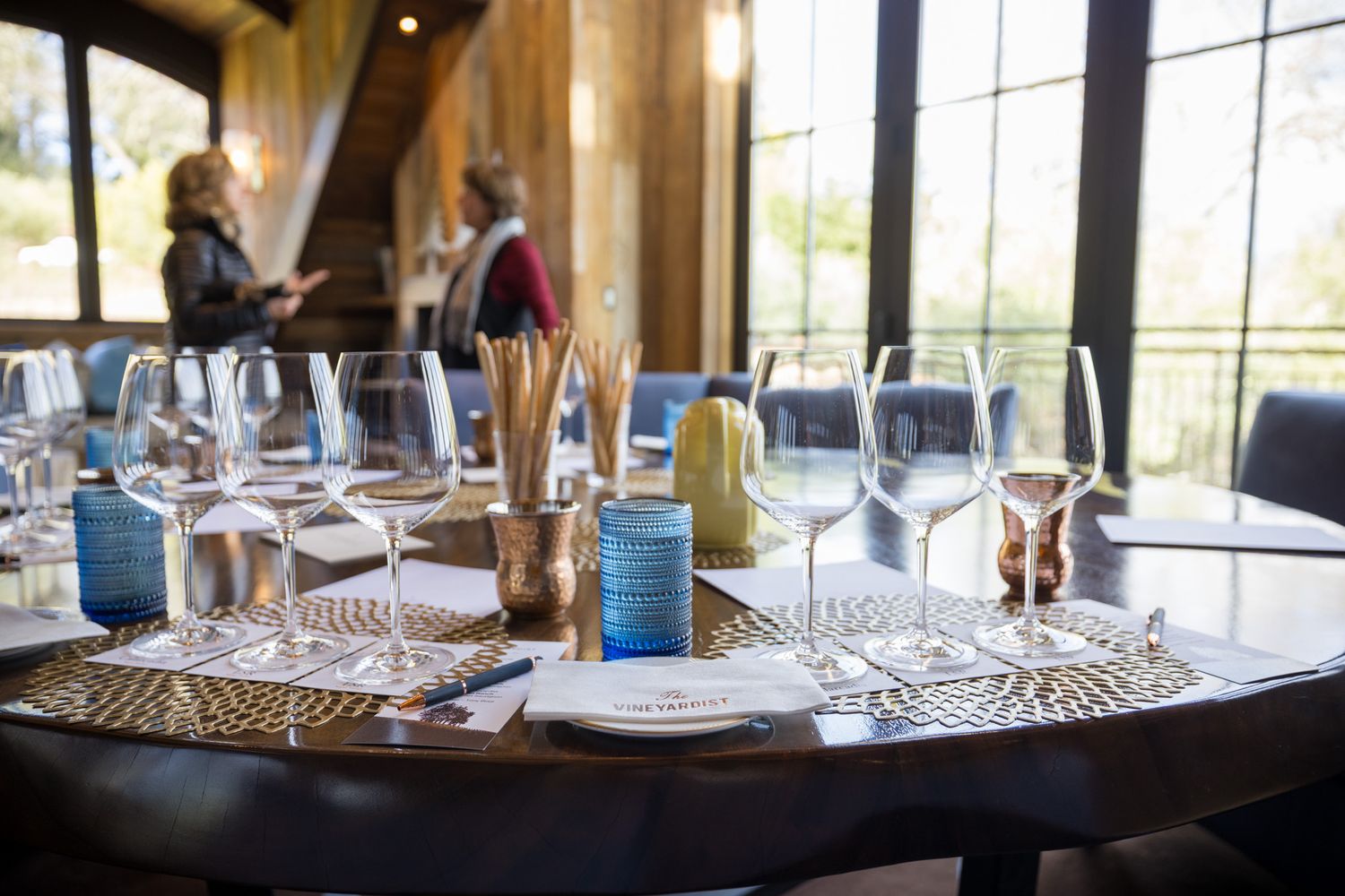 Formal table setting with wine glasses and blue accents in an upscale restaurant interior.