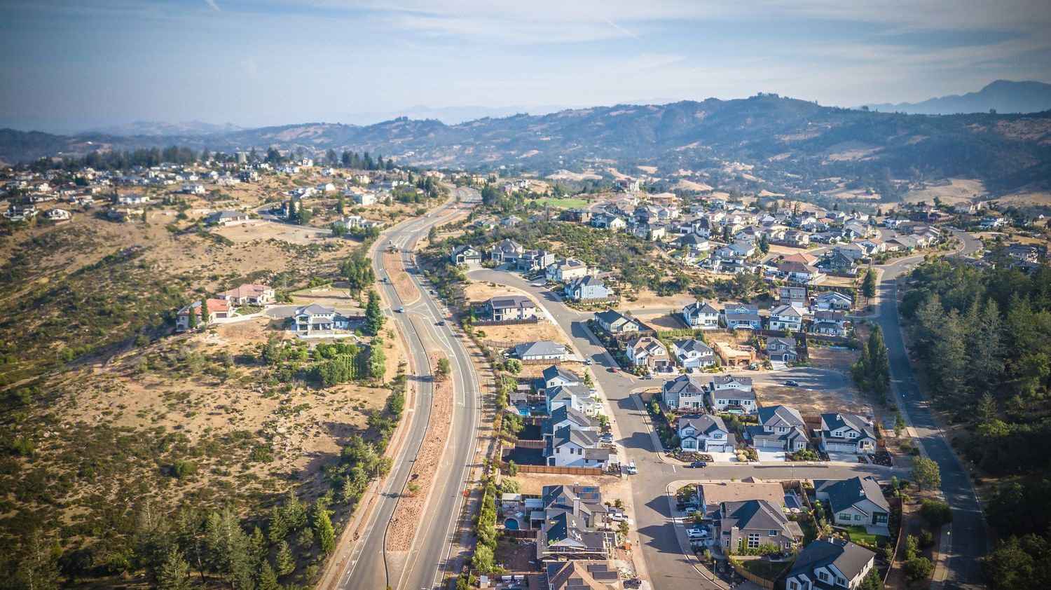 Aerial view of a suburban neighborhood with winding roads nestled among hills.