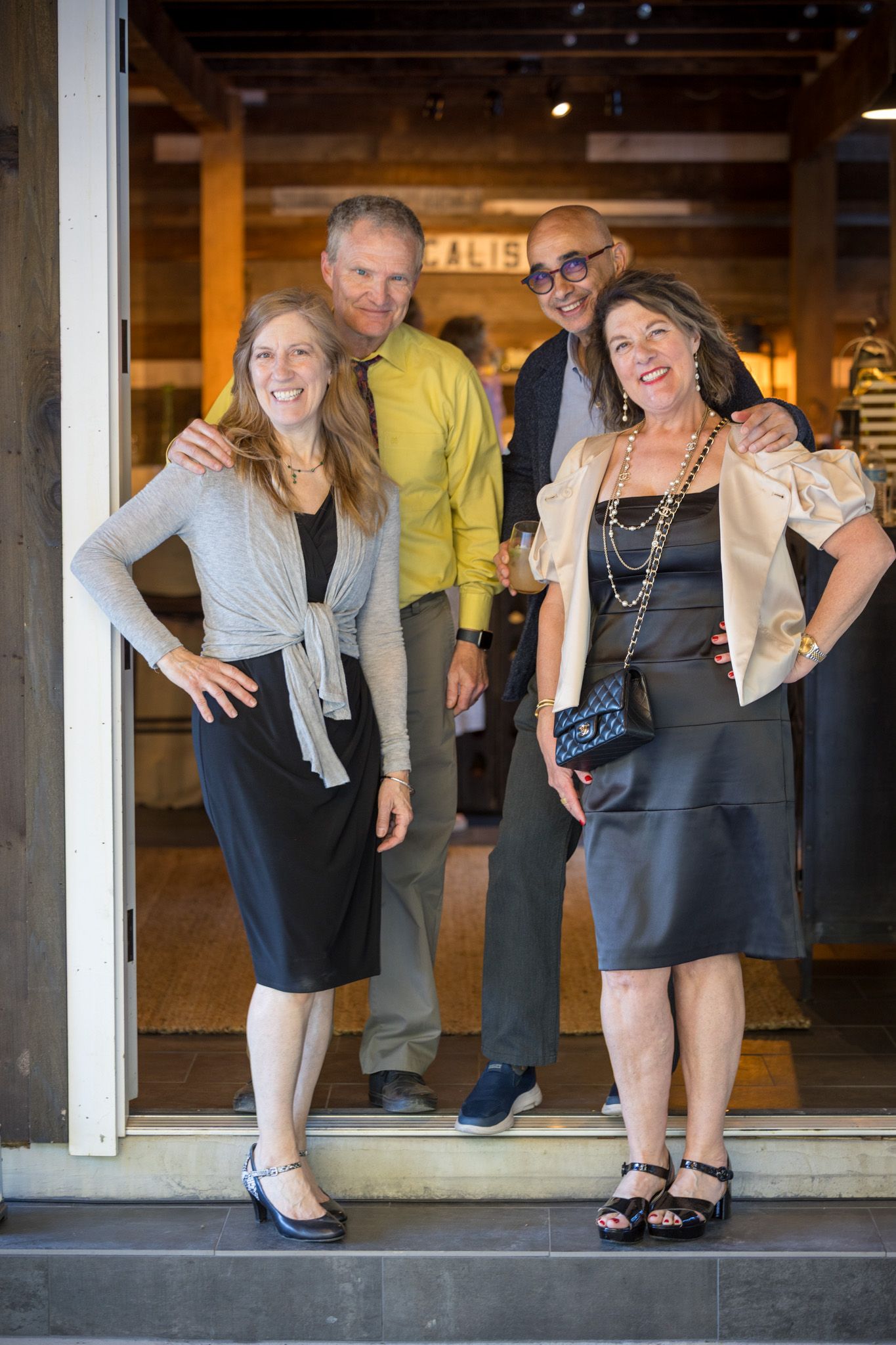 Four well-dressed professionals stand smiling in a doorway during a business gathering.