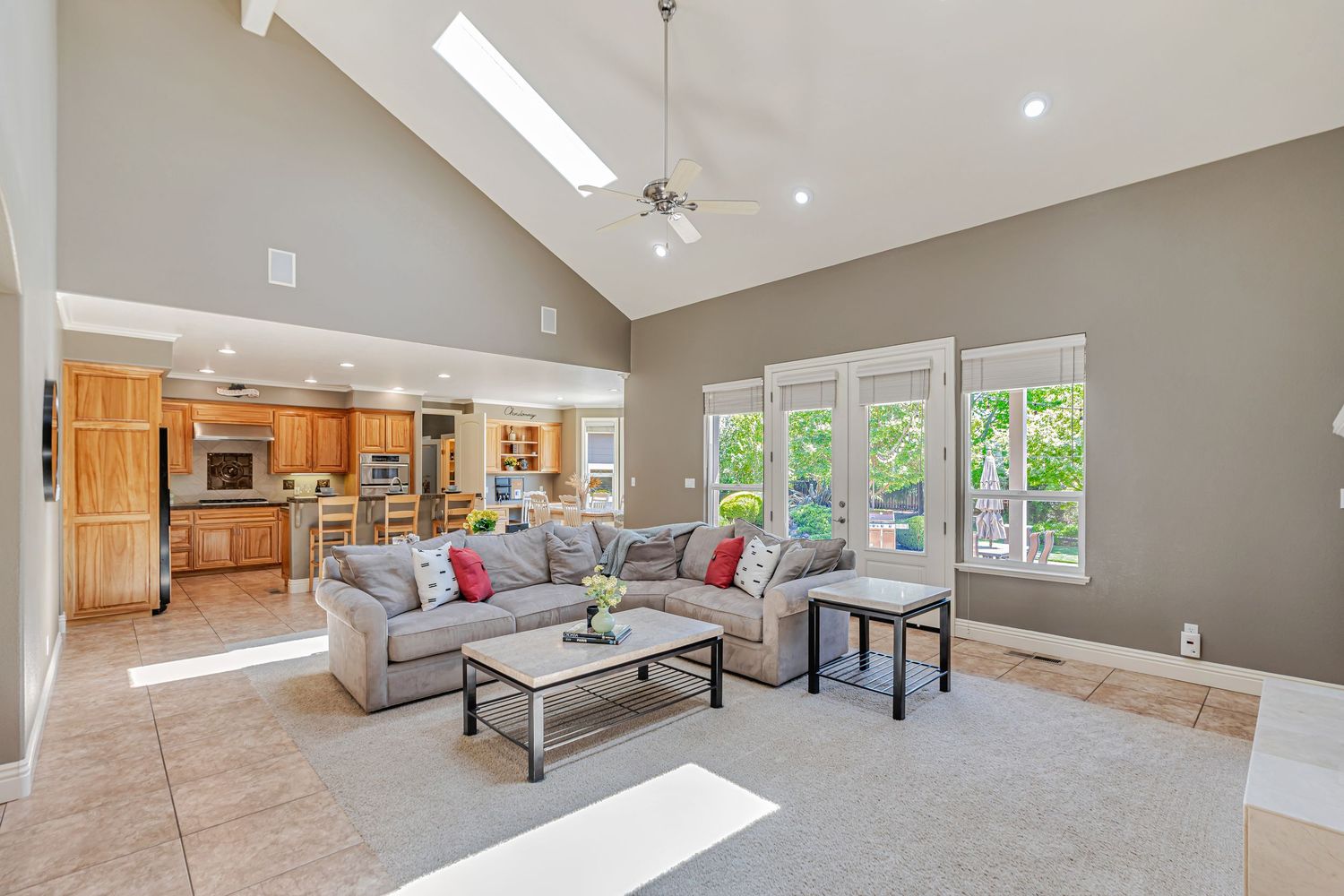Open concept living room with vaulted ceiling, skylights, and comfortable gray sectional sofa.