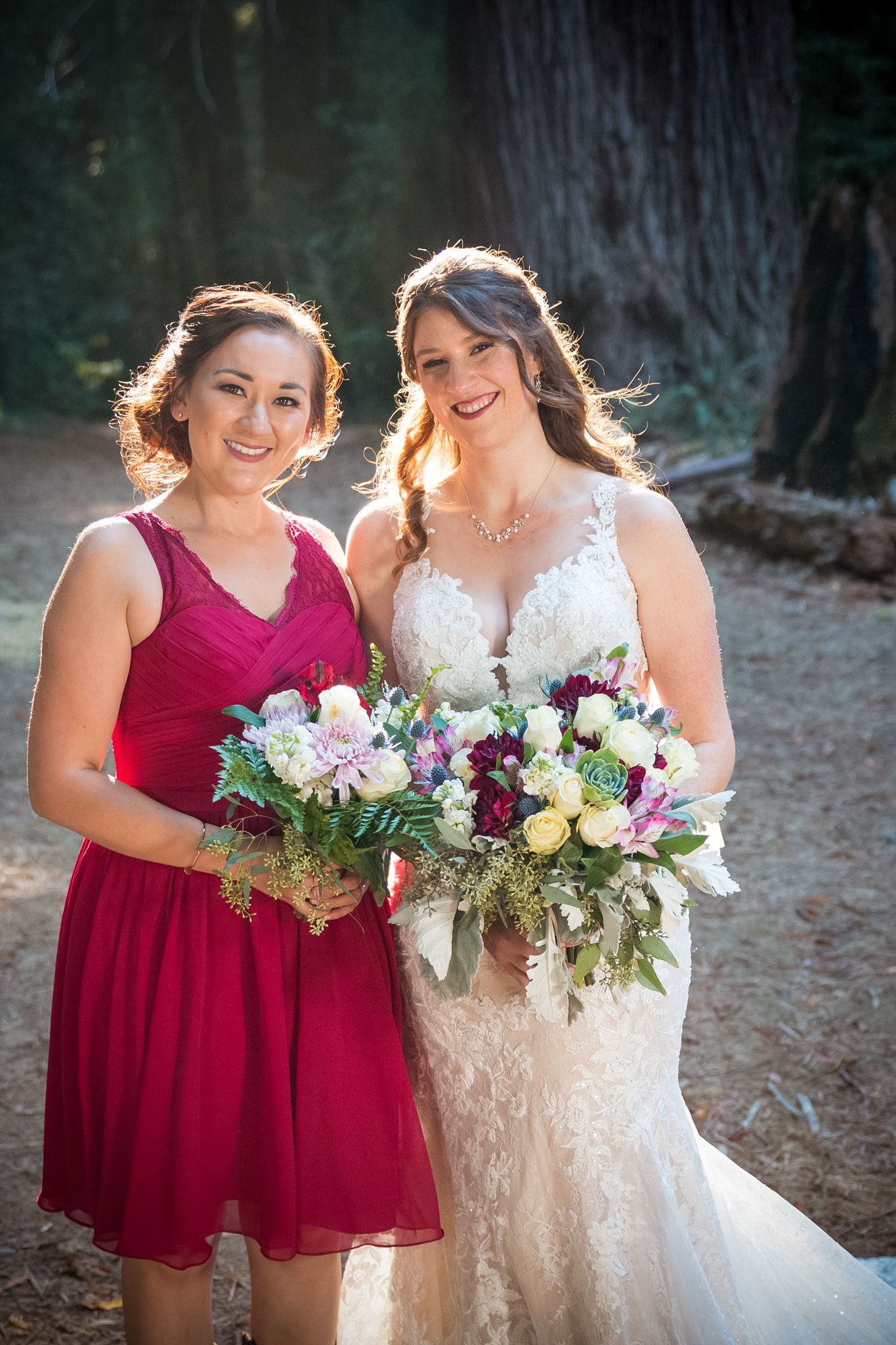 Wedding party members showcase elegant dresses and bouquets against forest backdrop.