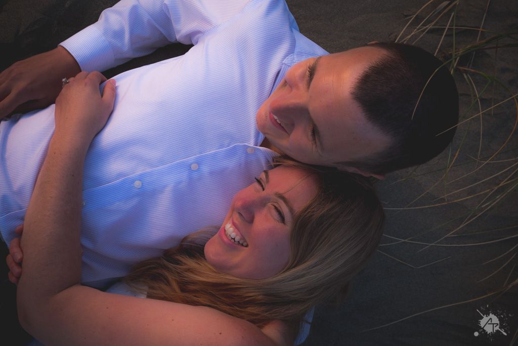A couple lying together intimately on dark background sharing a joyful moment.