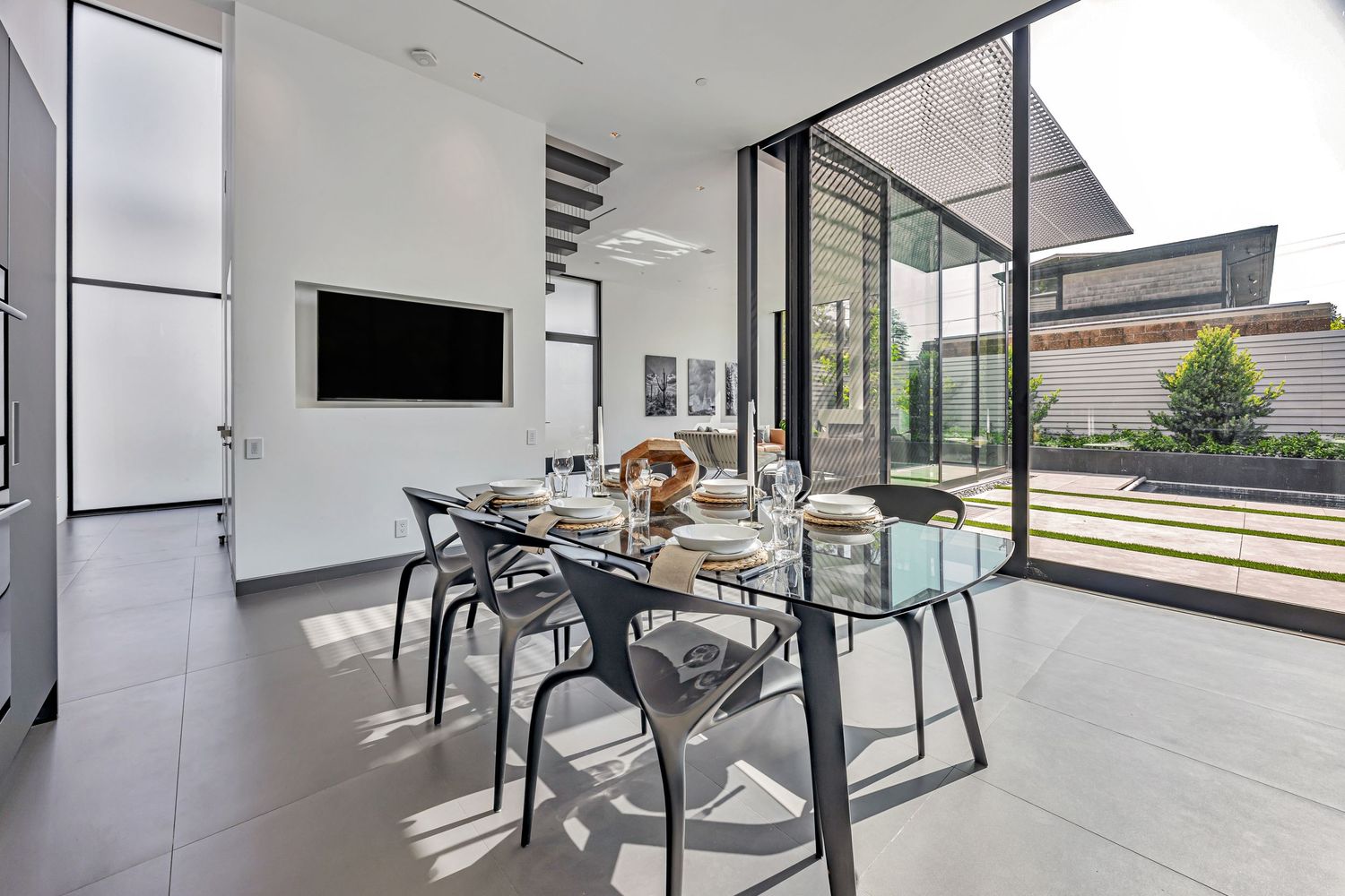 Industrial-style grey kitchen with matte black cabinets and large glass windows providing natural illumination.