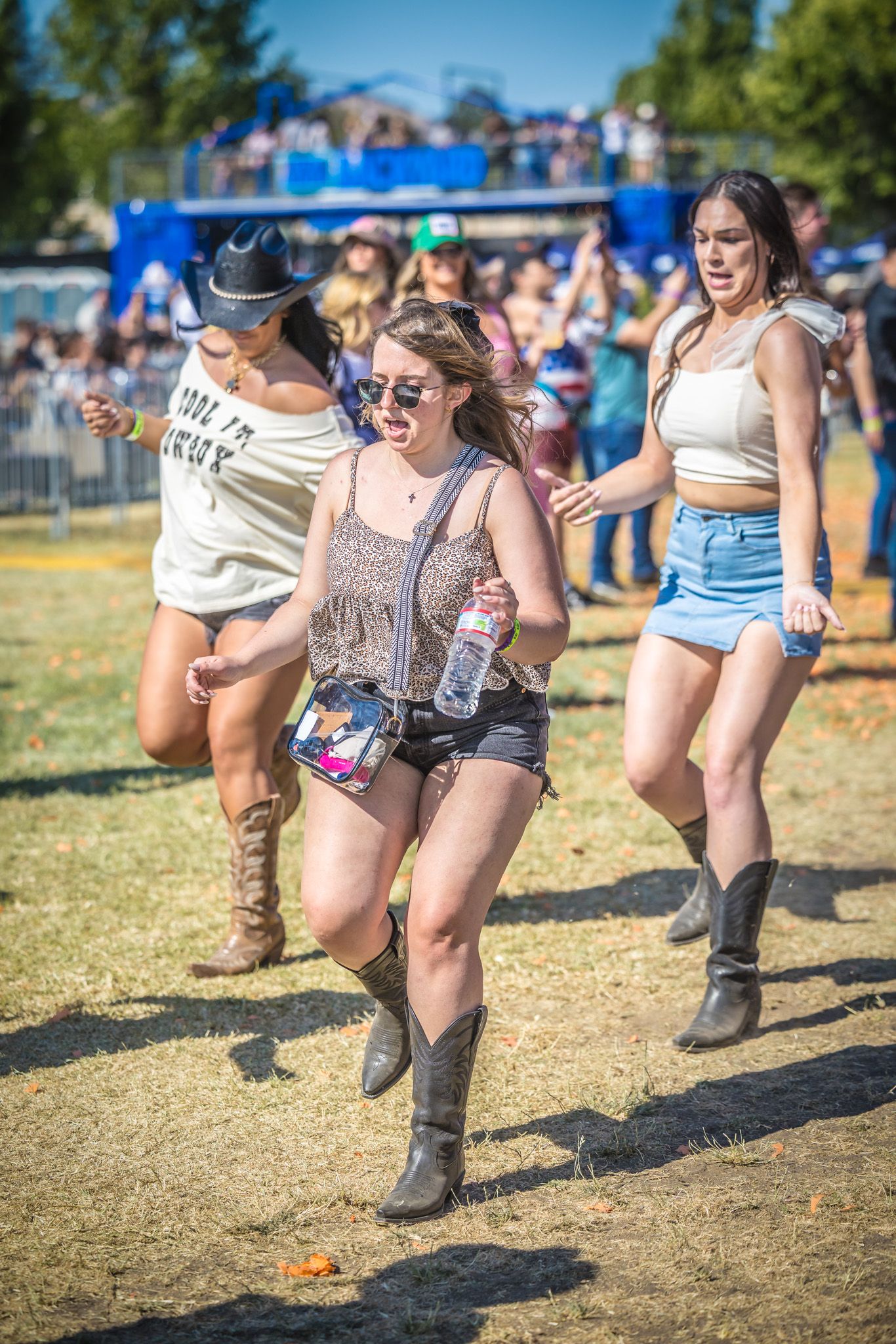 A sequence of photos showing cowboy boots and people dancing in a playful line dance formation at an outdoor festival.