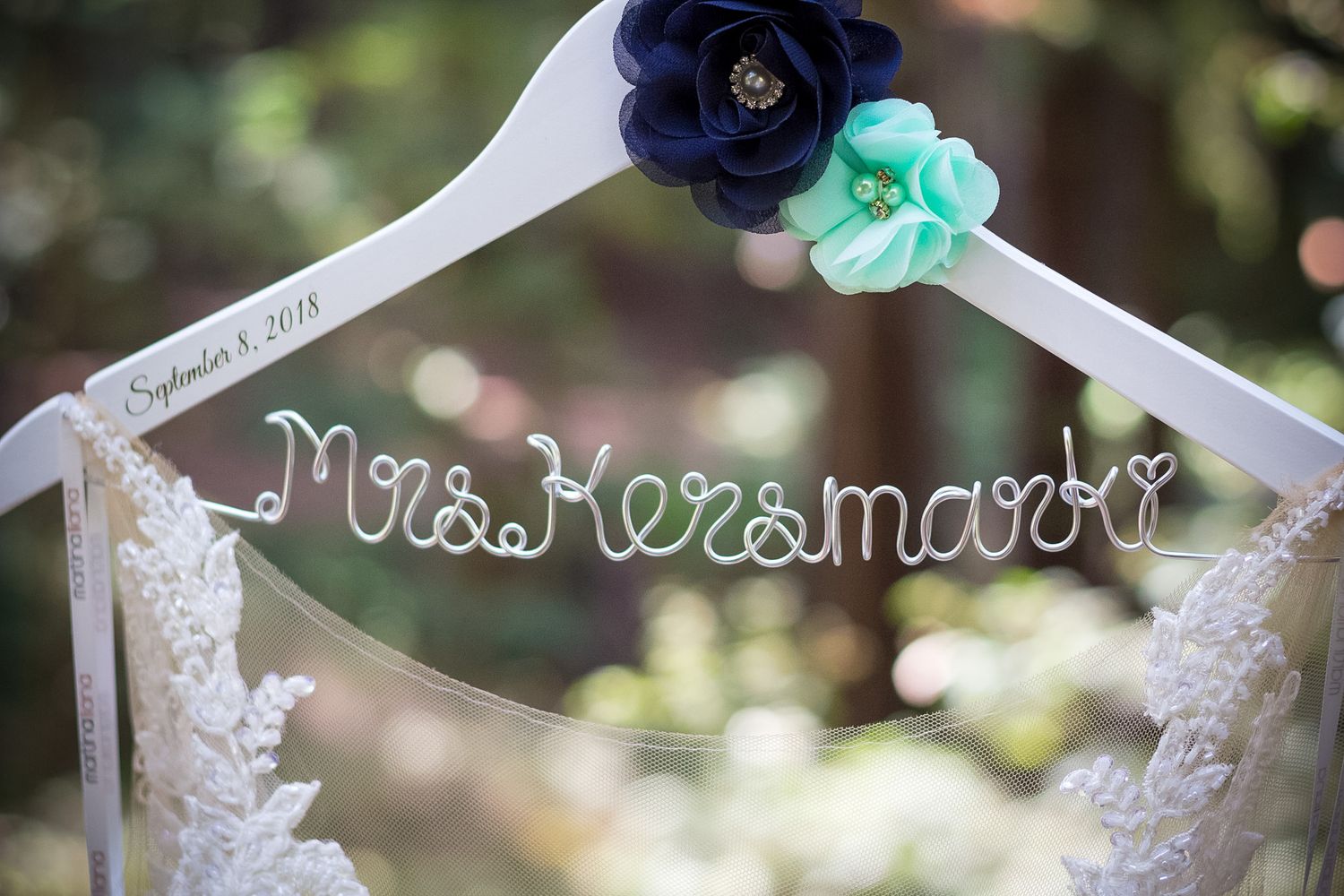 A decorative wedding hanger displays 'Mrs Kramaroff' with blue and mint floral accents.