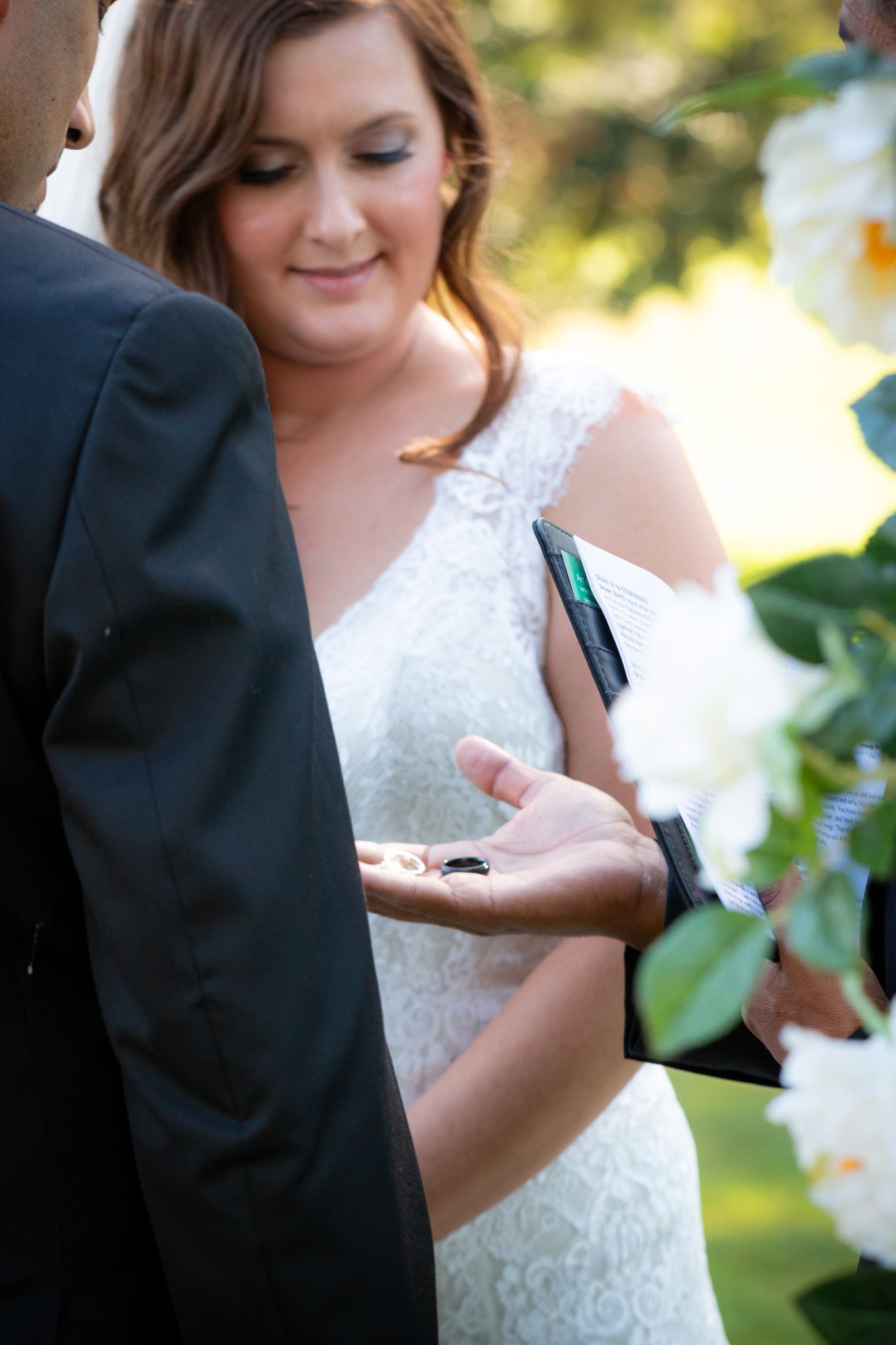 Close-up of bride in lace dress during outdoor wedding ceremony.