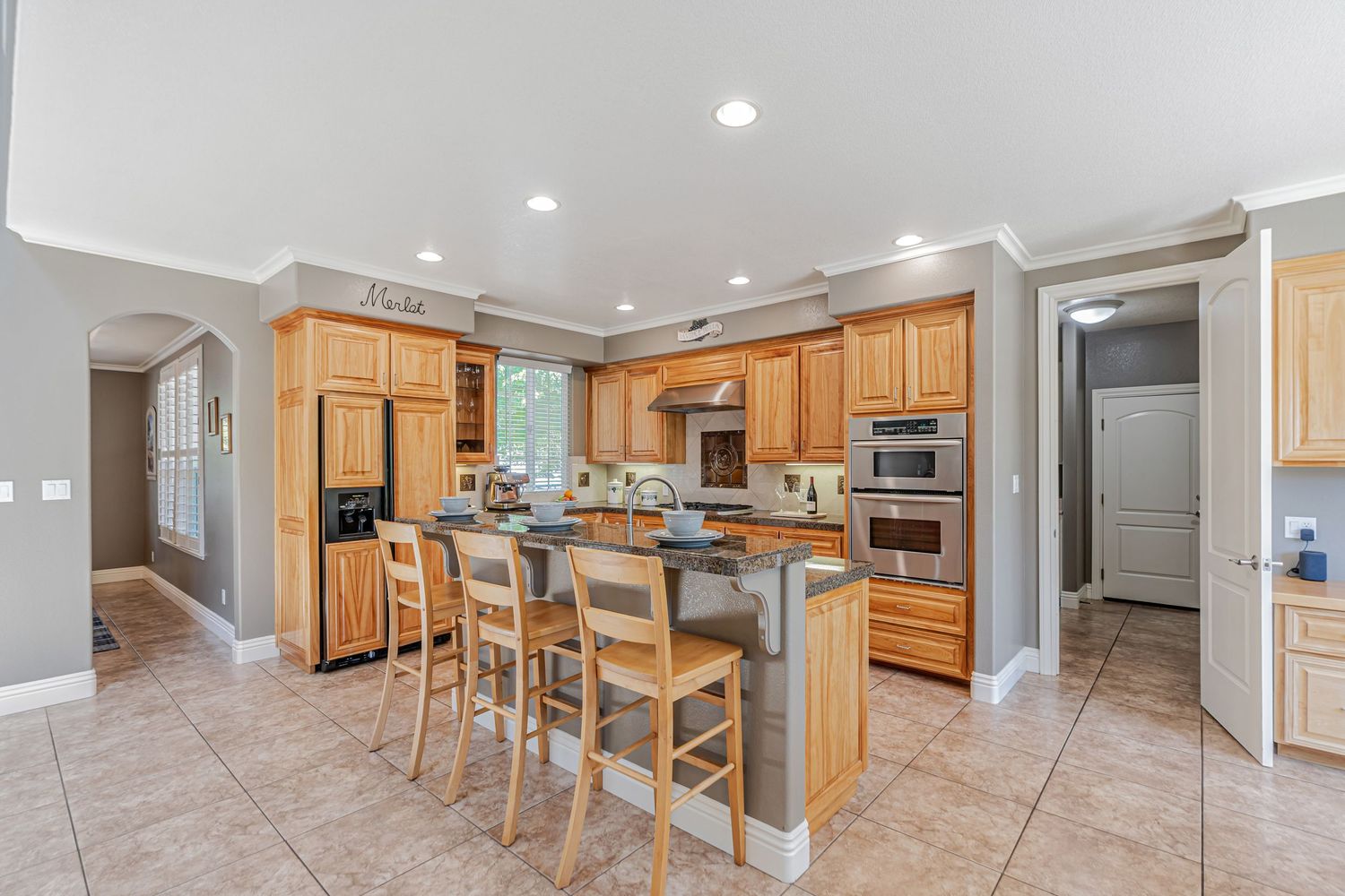 Spacious kitchen featuring wooden cabinetry, island with bar seating, and tiled flooring.