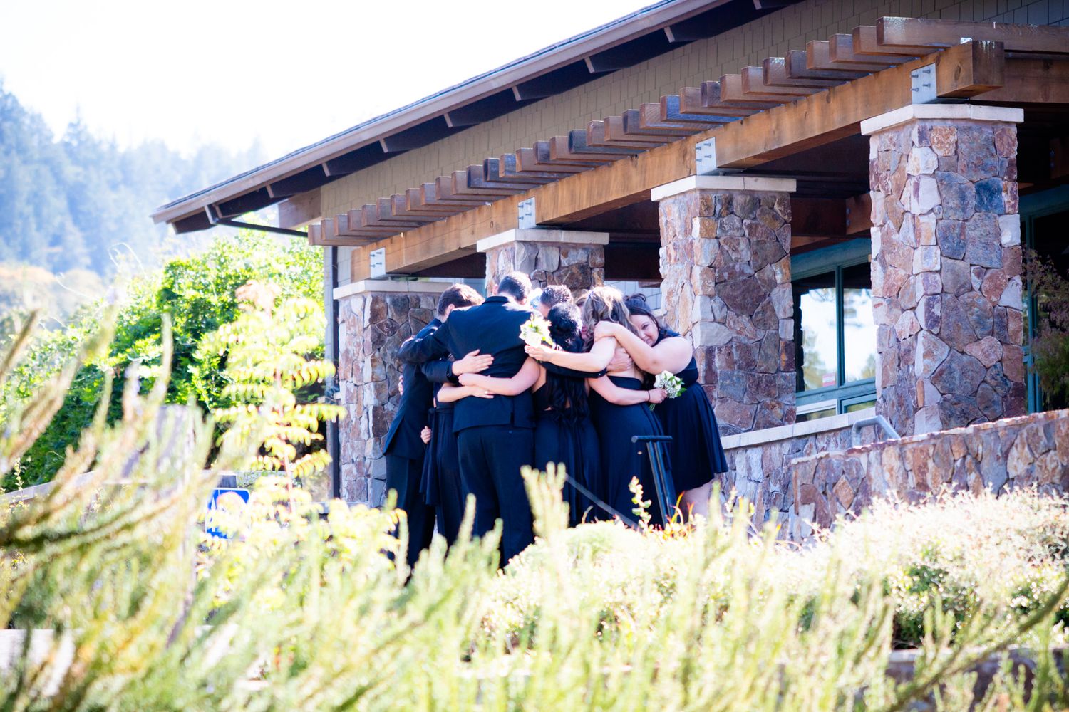 Wedding party gathers on stone patio of rustic mountain lodge.