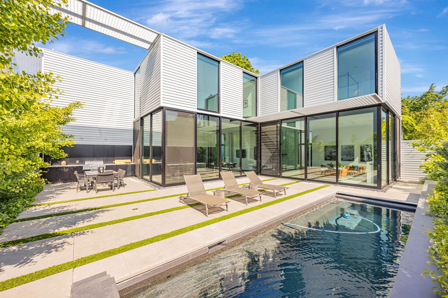 Luxurious modern home with floor-to-ceiling windows and lap pool in the backyard.