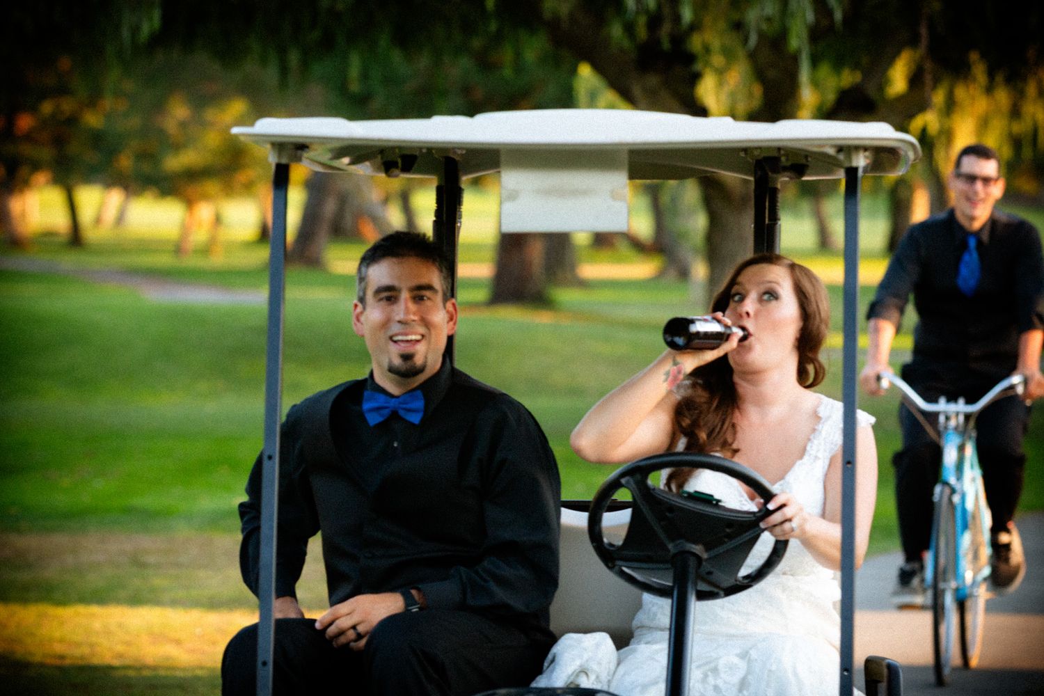 Playful couple riding in a golf cart during sunset at their wedding celebration.