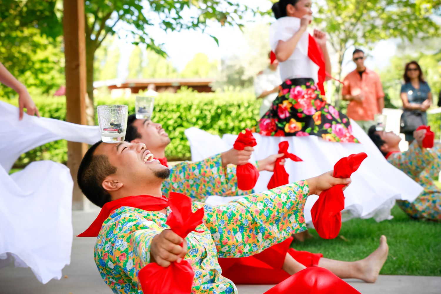 Dancers in colorful outfits performing traditional limbo dance at outdoor celebration.