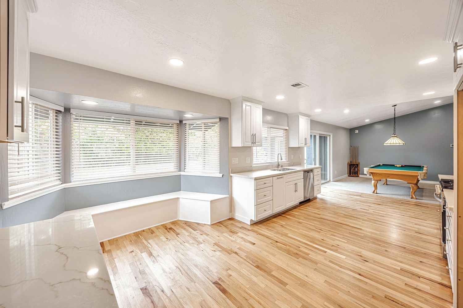 Modern open concept kitchen and living space with hardwood floors and built-in window seating.