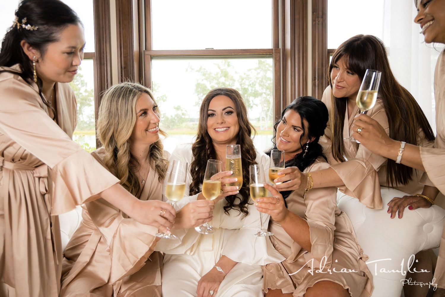 Wedding party in matching robes share champagne and laughter.