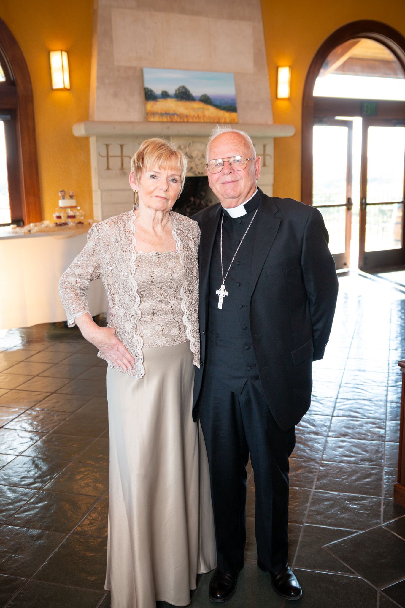 Formal portrait of couple in formal attire standing on tiled floor with arched doorway.