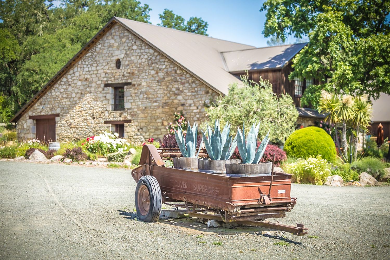 Vintage truck bed display filled with wine bottles outside a stone winery building.