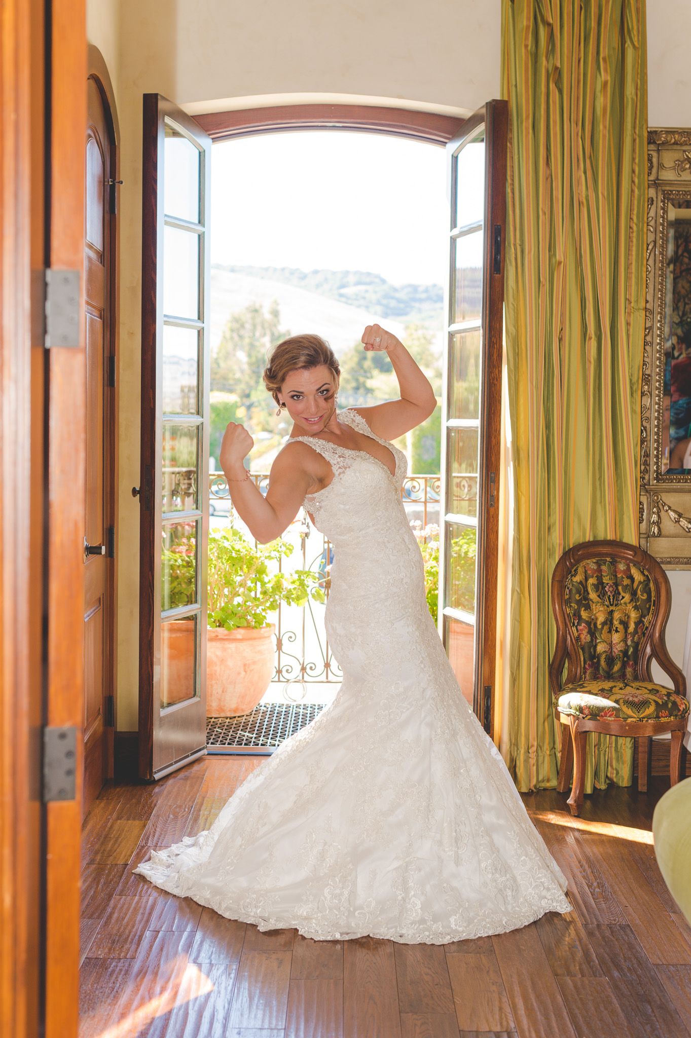 Elegant lace mermaid wedding dress with sweetheart neckline shown in sunlit villa doorway with bright outdoor view.