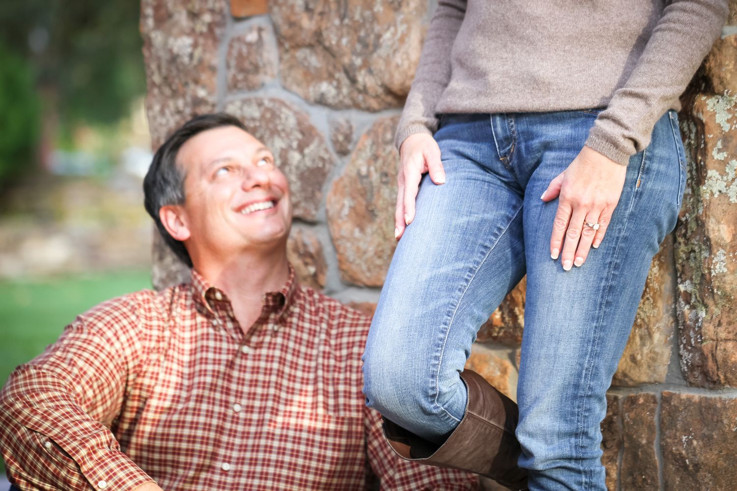 Candid moment between couple by stone wall in outdoor garden setting.
