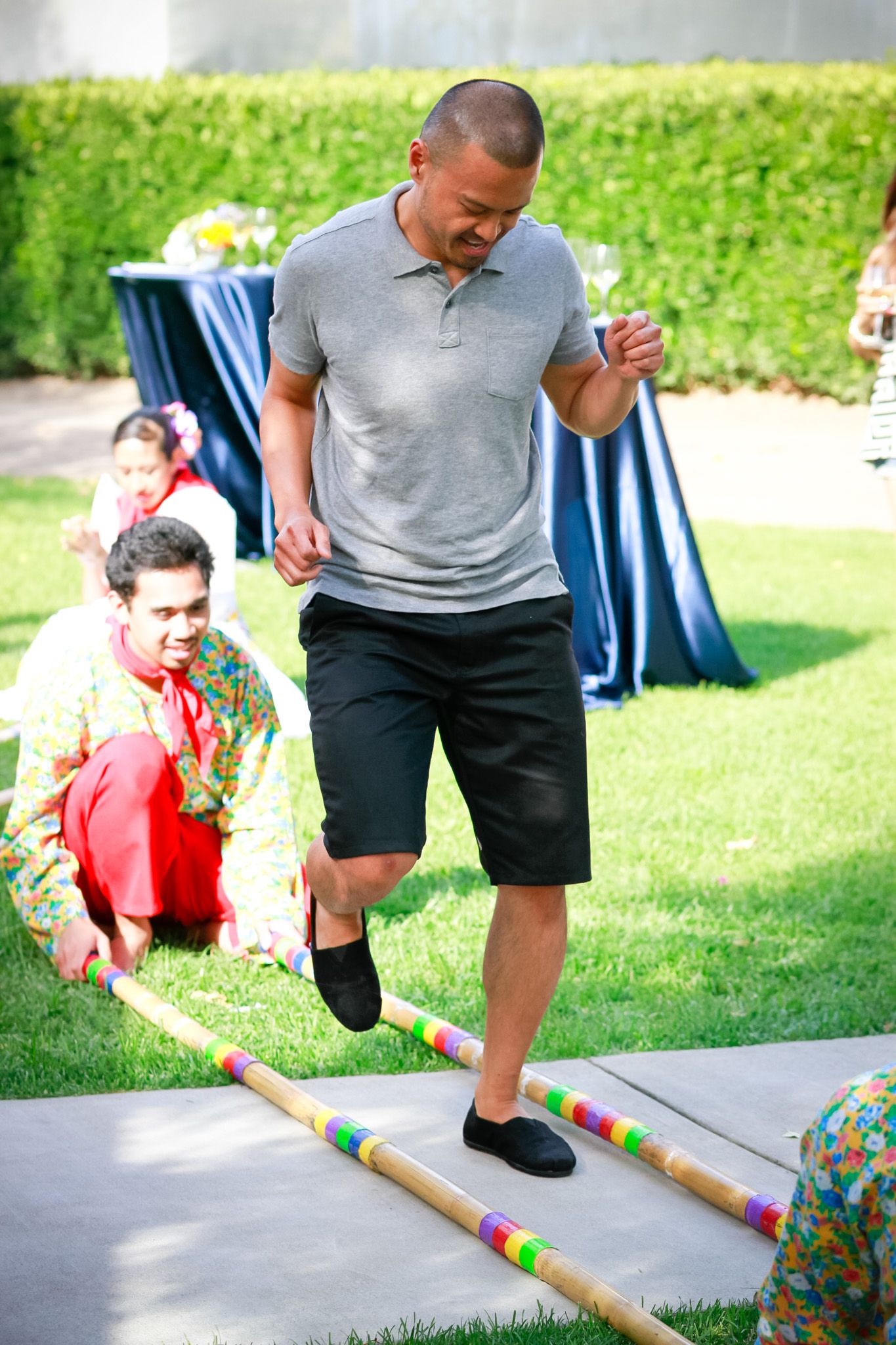 Participant carefully stepping over bamboo poles during traditional game or performance.