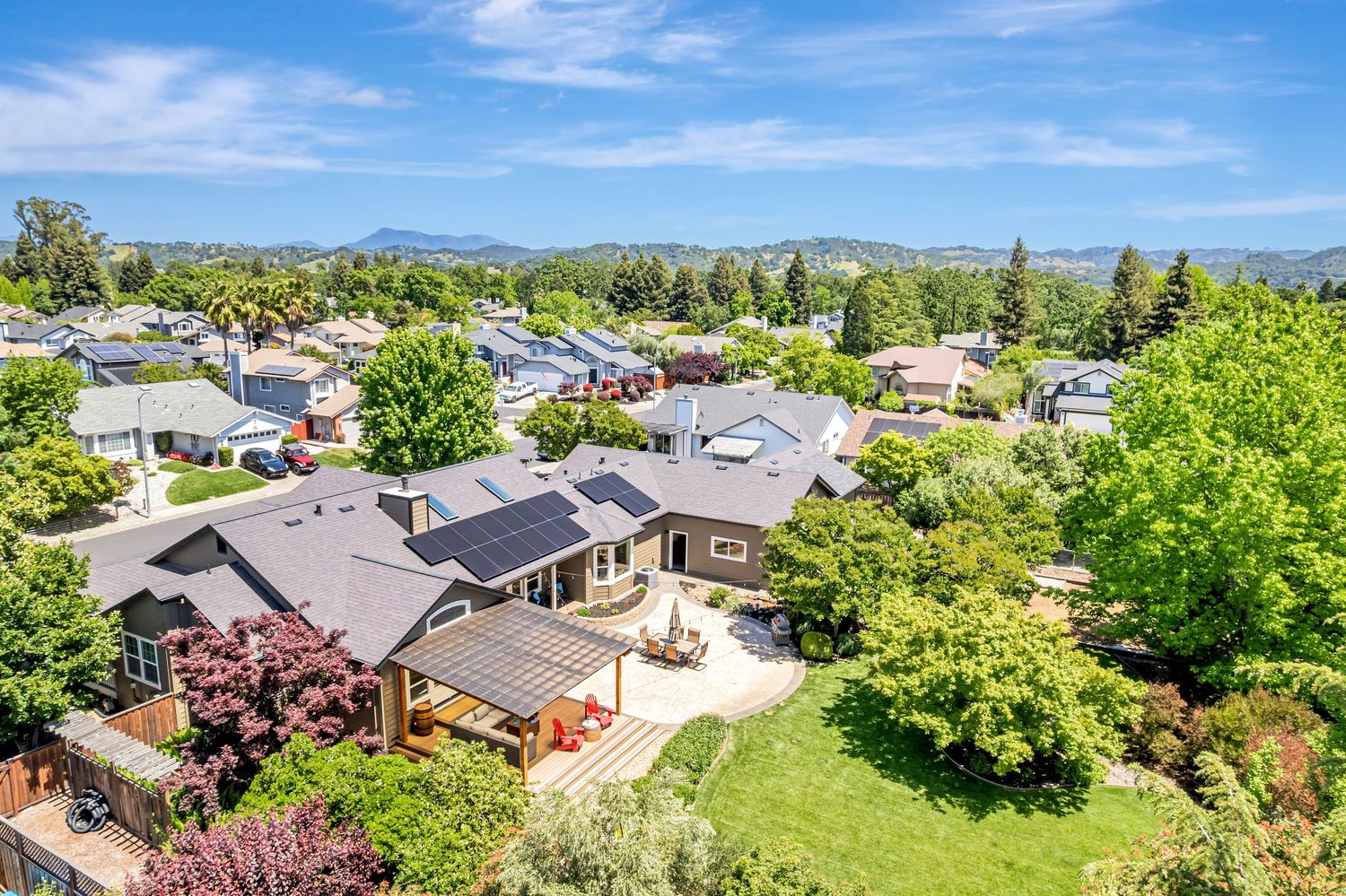 Aerial photograph of upscale residential homes with landscaped yards and mountain views in the background.