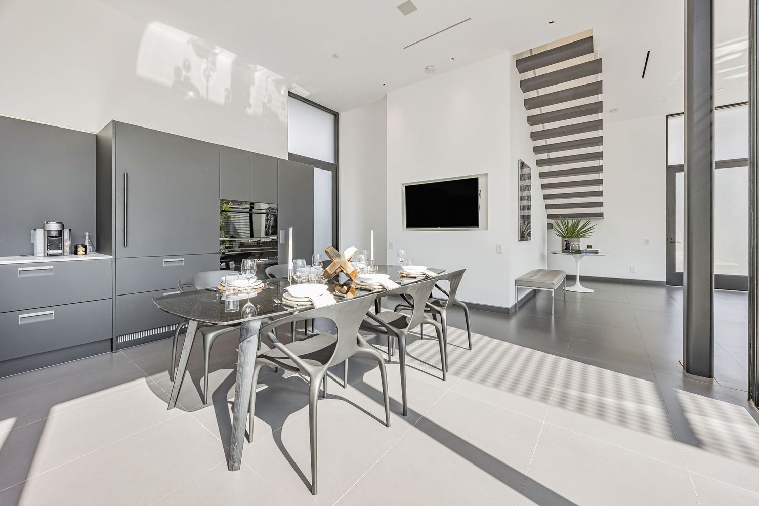 Sleek white kitchen featuring modern appliances and a long island with integrated sink and dining space.