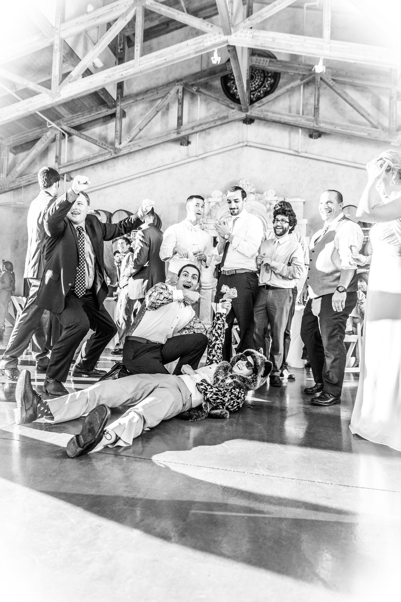 Black and white photo showing a lively dance party scene with people laid back on a dance floor in a warehouse-style setting.