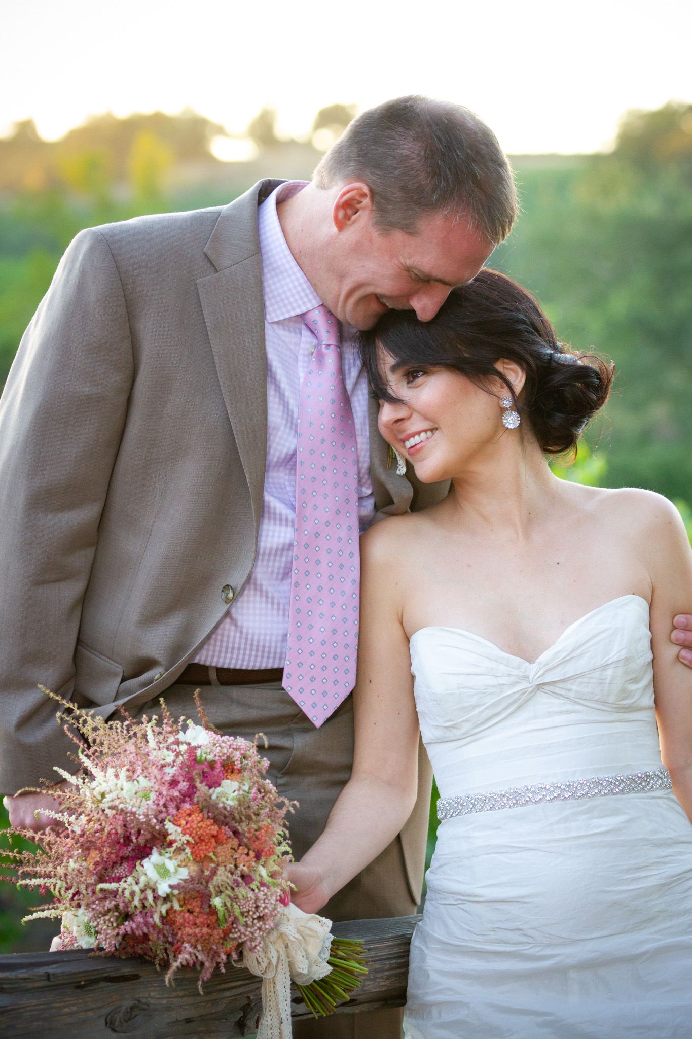 Romantic wedding moment with dried flower bouquet against sunset-lit natural backdrop.