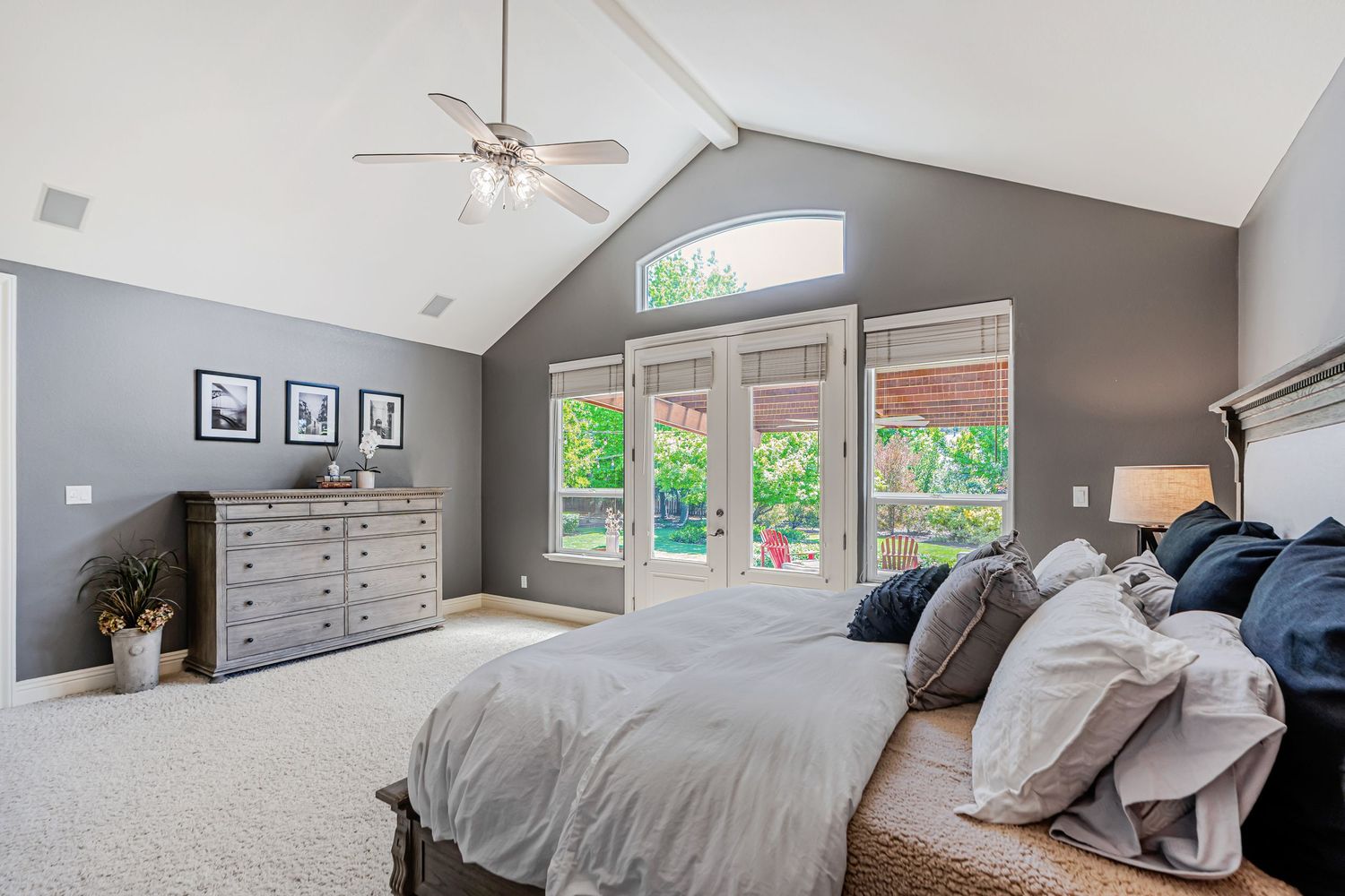 Modern master bedroom with vaulted ceiling, gray walls, large windows, and white bedding in a contemporary style.