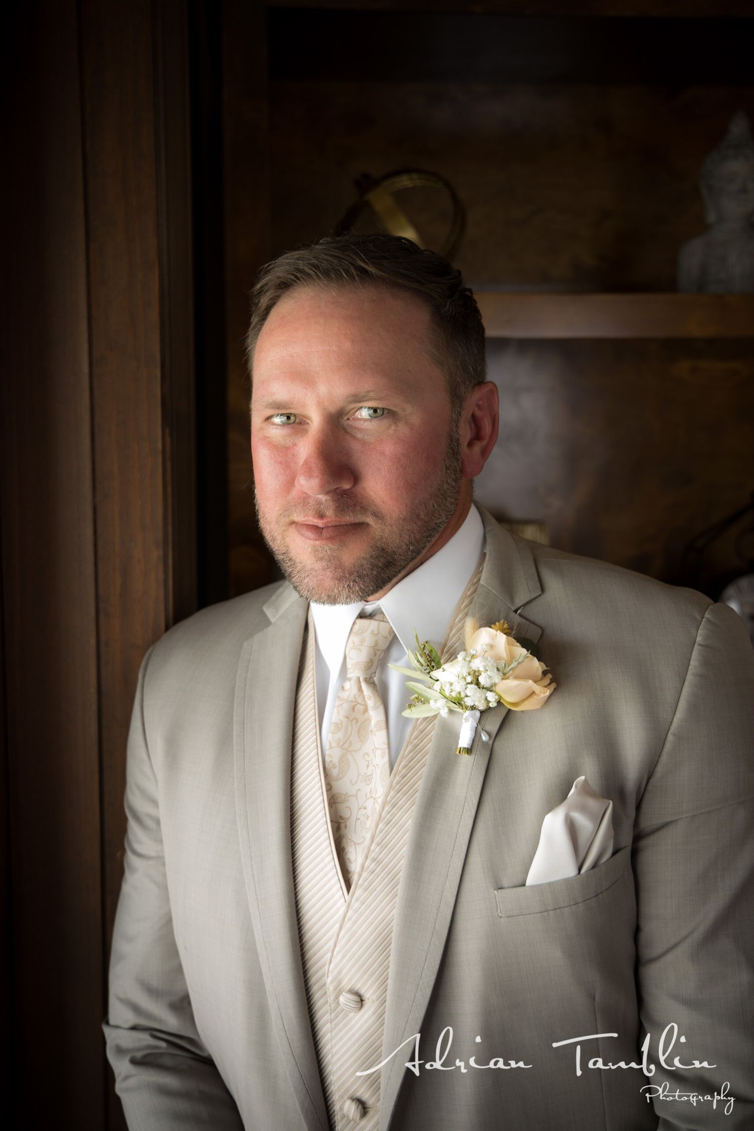 A formal portrait features a light gray tuxedo with matching vest and white boutonniere.