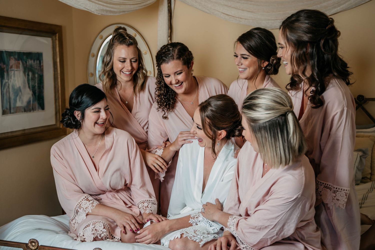 Bridesmaids in pink robes share an intimate moment while getting ready.